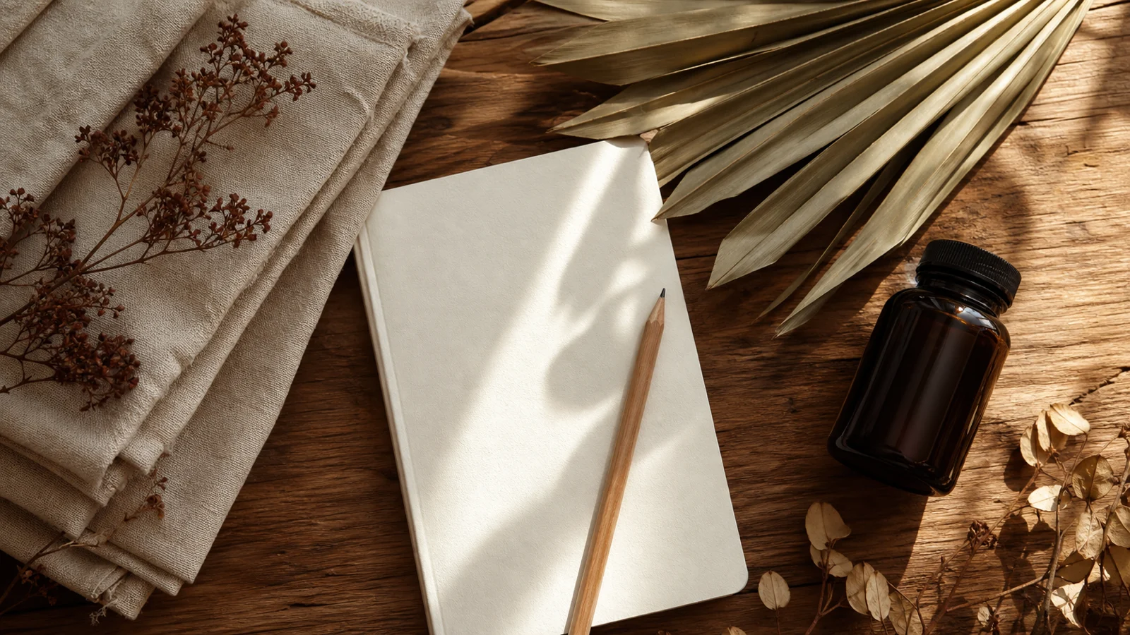 Notitieboek en neutraal flesje op een warme houten werktafel