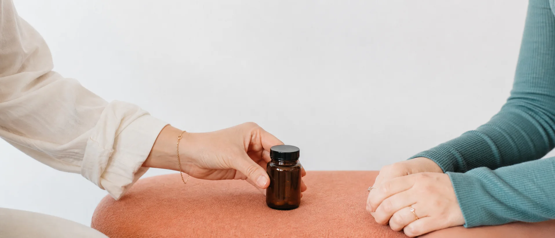 Twee vrouwen bespreken rustig een onbedrukte supplementfles tijdens een coachgesprek