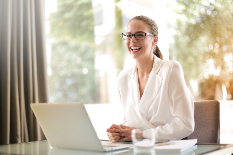 Vrouw werkt zelfverzekerd aan een bureau in een warm, licht interieur